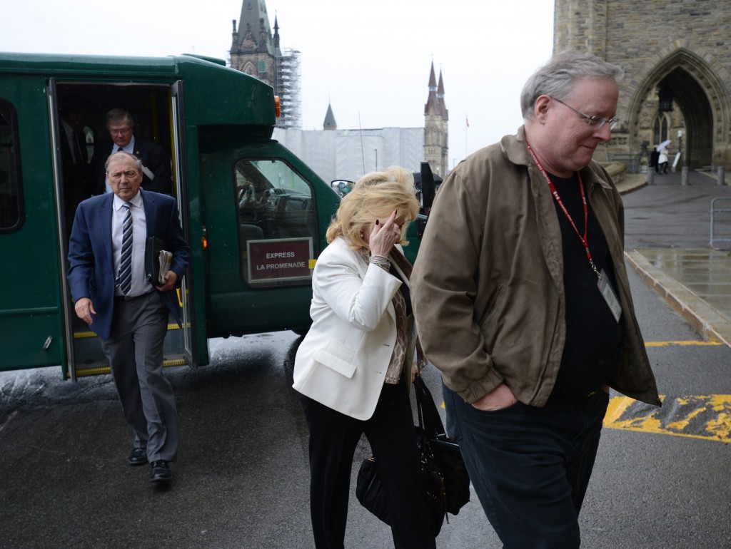 An unidentified man shields Sen. Pamela Wallin from media cameras as she arrives at the Senate entrance on Parliament Hill in Ottawa, Thursday, June 6, 2013. THE CANADIAN PRESS/Sean Kilpatrick